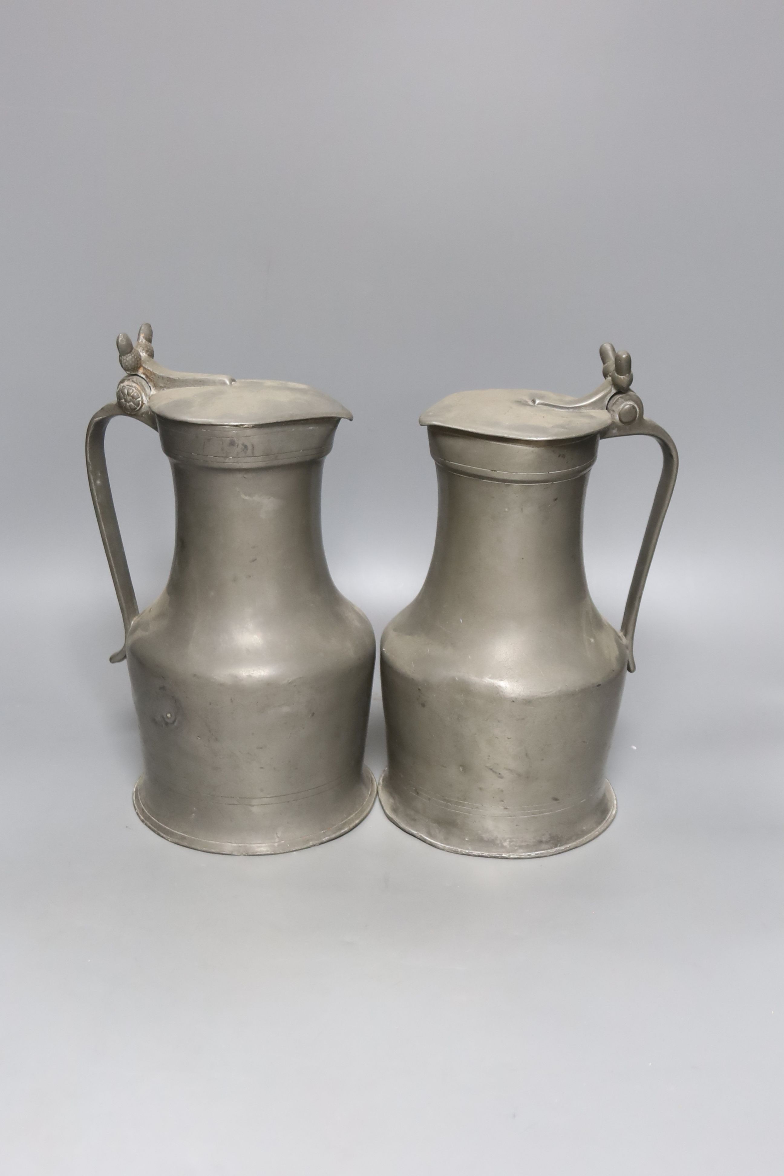 An 18th century French lidded pewter jug with double acorn thumbpiece and another similar jug, tallest 27cm